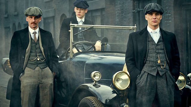 The main characters in the Peaky Blinders gang dressed up and sat on a 1920s open top car