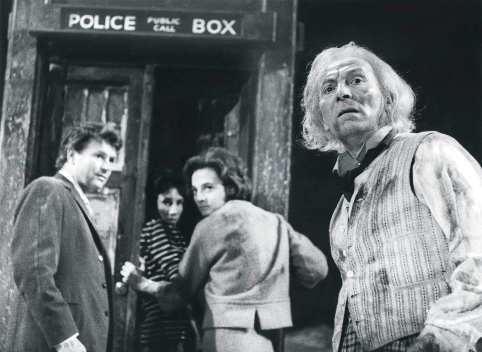 Doctor Who, from 1963, enters the TARDIS (which looks like a police box) with his companions.