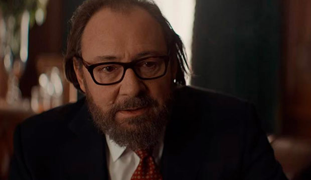 The character Hubert Pellegrini (Hervé Pierre) wearing a suit with a tie looking tense.