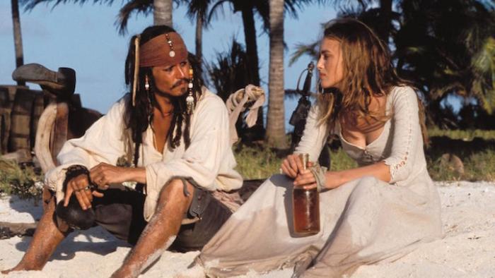 Johnny Depp as Jack Sparrow and Keira Knightley as Elizabeth Swann in Pirates of the Caribbean: The Curse of the Black Pearl. They are sitting on a  Caribbean beach discussing life. 
