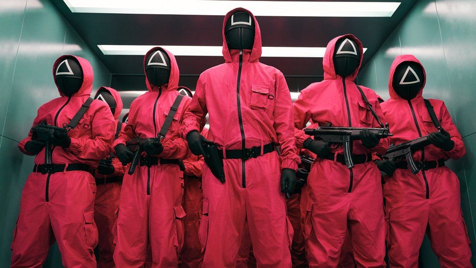 The guards that coordinate the games are dressed in pink suits and don masks resembling video game symbols.