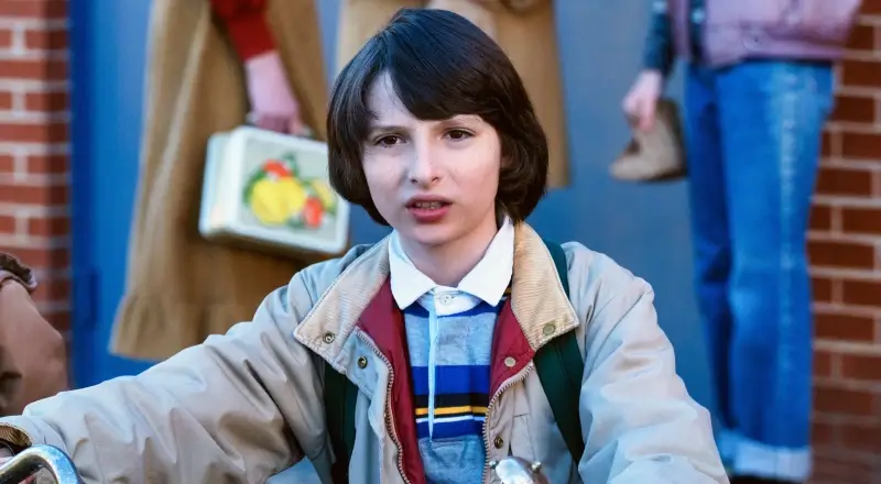 Mike Wheeler from Stranger Things dressed in a colorful jumper with an 80s style haircut