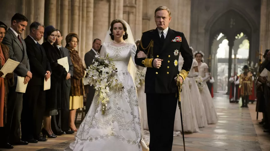 Princess Elizabeth wearing a white traditional wedding dress being led down the aisle by The King.