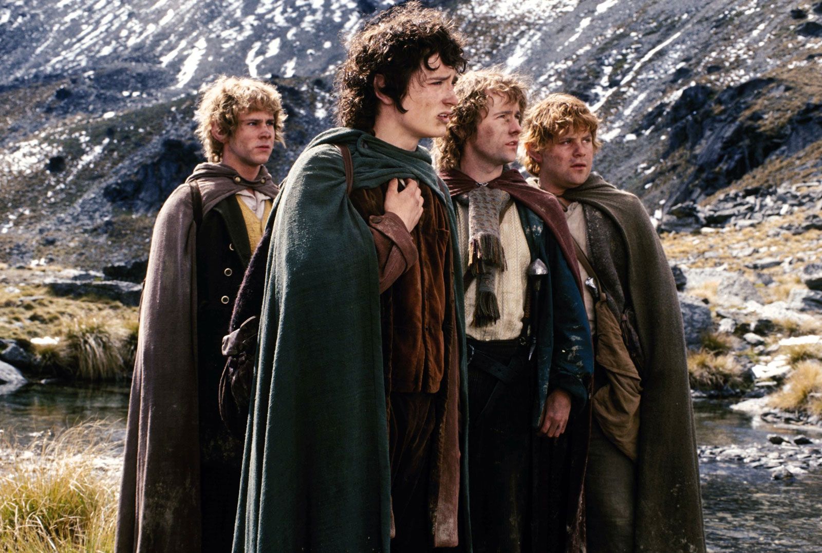 Frodo Baggins, the main protagonist in Fellowship of the ring surrounded by Sam and the others  in the mountains.