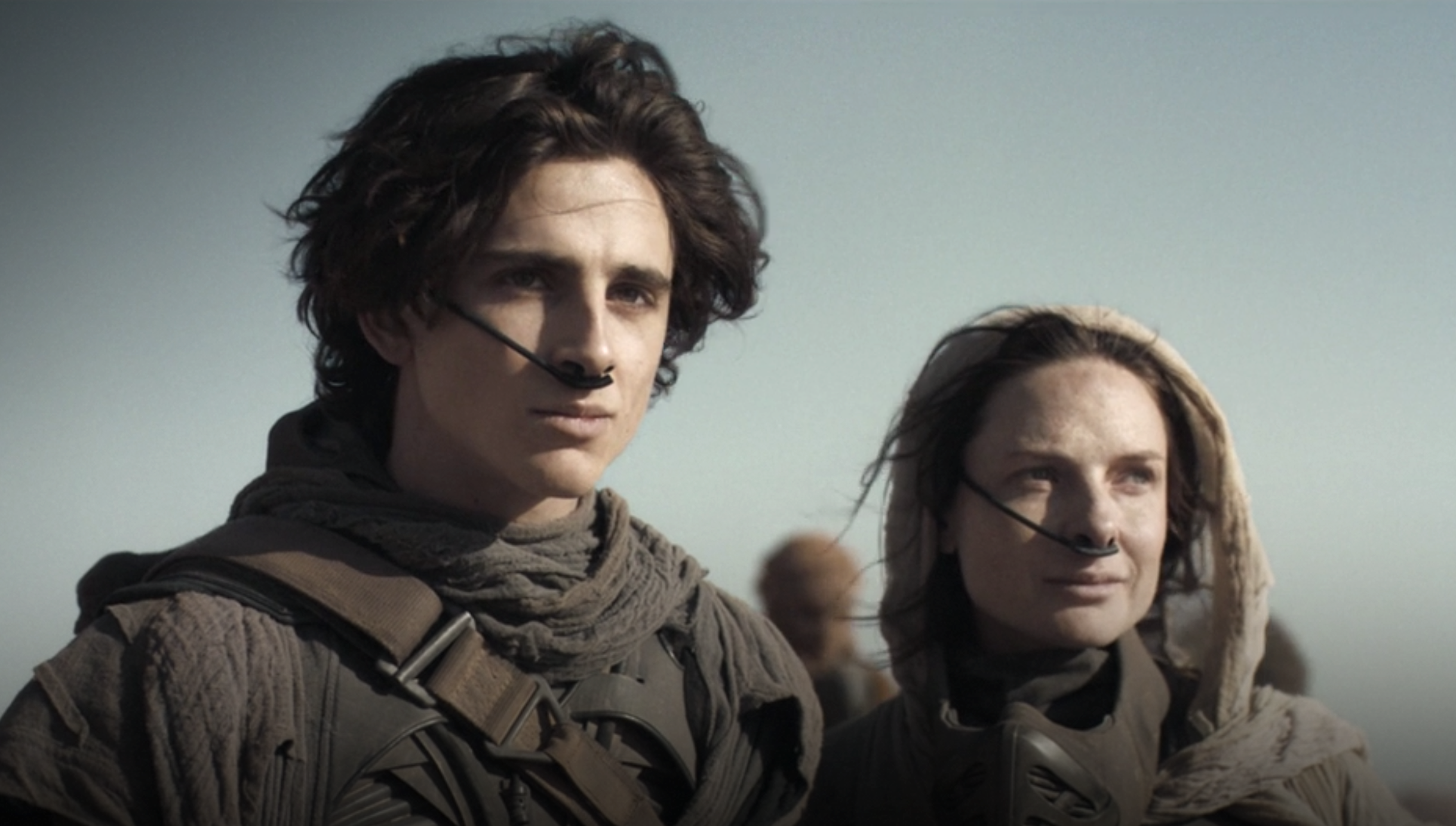 The main characters from Dune, a man and a woman, stare off into the distance.i