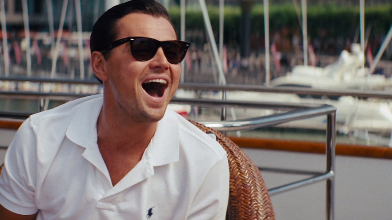 Jordan Belfort the main character in Wolf of Wall Street in a white polo shirt on a boat pulling a funny face