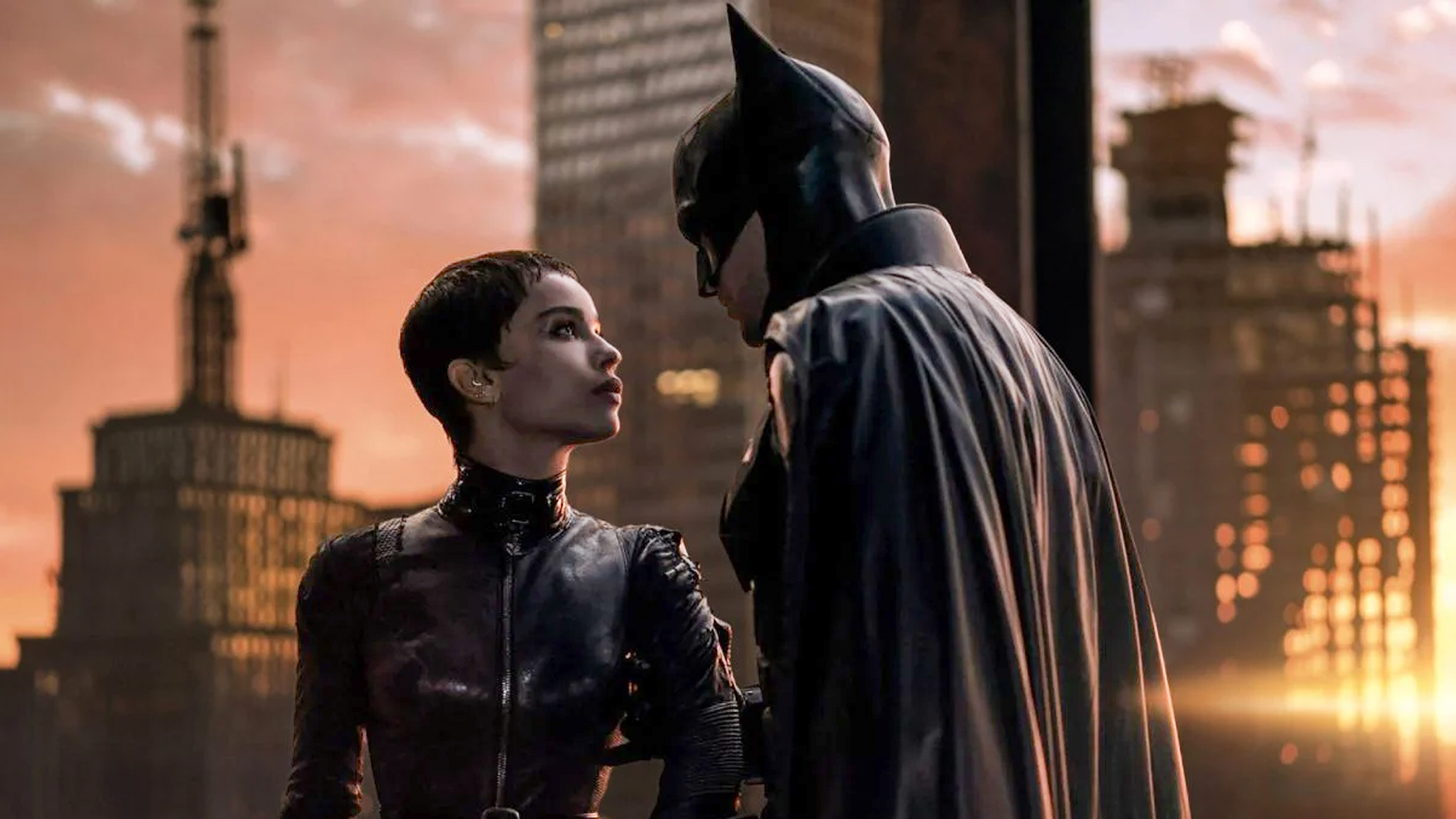 Batman and Catwoman stand together on the top of a building in Gotham.