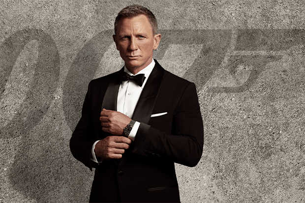 James Bond stands in front of a gray wall.
